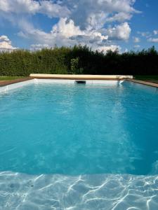 a large swimming pool with blue water at SUITES EN PERCHE-Proche Mortagne in Bures