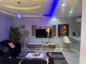 a living room with a couch and a tv at Résidence imeris mbour 8 chambres in Dinnguiraye
