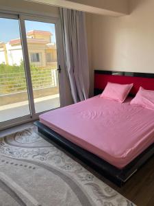 a bed with pink sheets in a room with a window at Villa Ayoun El Nakheel Luxury Family Stay with Garden and Pool in Sphinx International Airport +74 photos