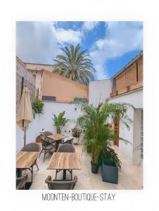 a patio with tables and chairs and palm trees at MOONTEN Boutique Stay in Sóller +44 photos