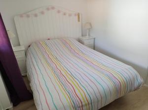 a bed with a multicolored striped comforter in a bedroom at Appartement proche Bordeaux in Cenon