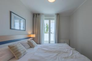 a white bed in a bedroom with a window at Bina an der Seebrücke Zingst in Zingst