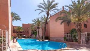 a swimming pool with palm trees in front of a building at Riad Four Rooms & Pool in Marrakesh