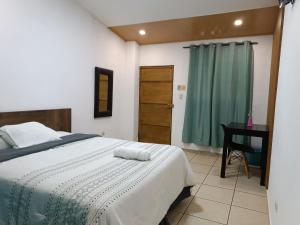 a bedroom with a bed with a desk and a green curtain at El Patio de Don Moncho in Nueva San Salvador +18 photos