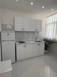 a white kitchen with a sink and a refrigerator at ELIO's Room in Durrës +38 photos