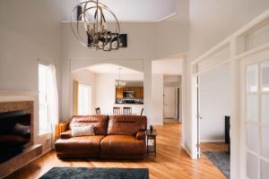 a living room with a leather couch and a chandelier at Cozy Retreat - King Beds - Cinema Cave & Home Gym in Westminster