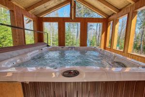 圣弗朗索瓦小河L'ours de Charlevoix - Chalet proche du Massif avec spa的带窗户的客房内设有一个大型热水浴缸