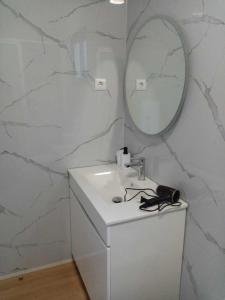 a white bathroom with a sink and a mirror at Vivenda Silva in Seixal