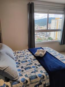 a bed with a towel on it in front of a window at Studio Novo Luxo - Centro in Mogi das Cruzes
