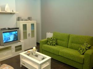 sala de estar con sofá verde y TV en Residencial Parque los Laureles, en Portonovo