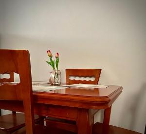 a wooden table with a vase of flowers on top of it at New Bazaar Cozy Villa in Tirana +2 photos
