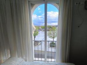 a bedroom with a large window with a view at Hostal Alhambra in Mocejón