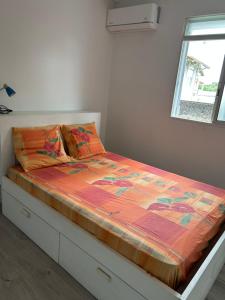 a bed with an orange comforter in a bedroom at Villa FRANNY in Fort-de-France +6 photos