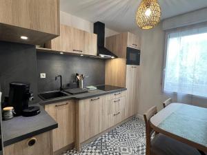 a kitchen with wooden cabinets and a table and a window at Appartement Nature au calme in Albi