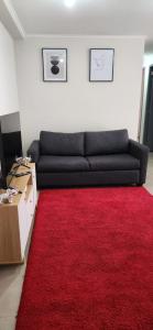 a living room with a black couch and a red rug at Dormitorio individual - Baño, Altos de San Miguel in Talca