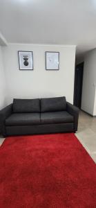 a living room with a black couch and a red rug at Dormitorio individual - Baño, Altos de San Miguel in Talca