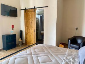 a bedroom with a bed and a chair and a sliding door at El Callejón HIERRO in Real de Catorce