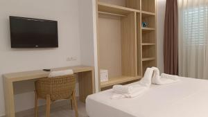 a hotel room with a bed with a tv and a chair at Hotel Roca Bella in Es Pujols