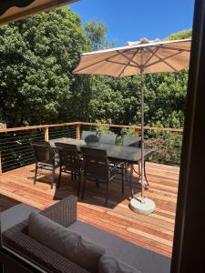 a wooden deck with a table and an umbrella at Valley House - Location Location Location - Comfortable home in the heart of Healesville in Healesville