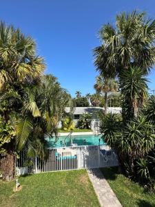 a pool with palm trees and a white fence at White Horse Motel in Lake Worth