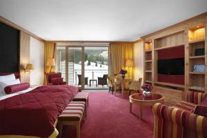 a hotel room with a bed and a living room at Kempinski Hotel Das Tirol in Jochberg
