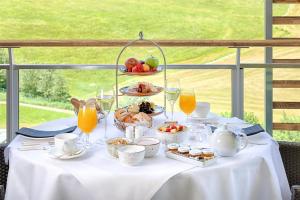a table with a plate of food and glasses of orange juice at Kempinski Hotel Das Tirol in Jochberg