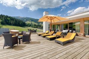 a deck with chairs and tables and an umbrella at Kempinski Hotel Das Tirol in Jochberg