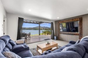 a living room with a blue couch and a large window at Kaitoke Retreat and Studio, 10 guests, Waterfront in Raglan