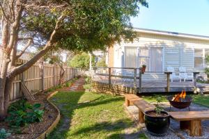a backyard with a wooden deck with a bench and a table at Sweet Az in Bicheno