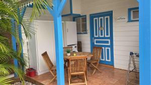 a patio with a table and chairs and a blue door at Bungalow Cocomarine in Sainte-Anne