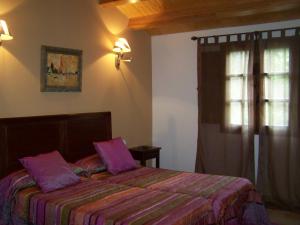 Un dormitorio con una cama con sábanas moradas y una ventana en A Casa de Mañas, en Mondoñedo