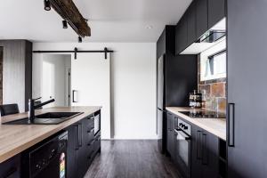 a kitchen with black cabinets and a sink at Kaitoke Retreat & Studio in Raglan +21 photos