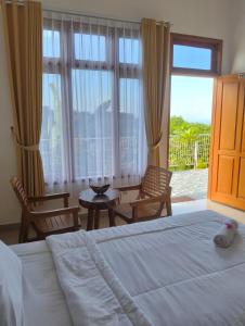 a bedroom with a bed and chairs and a large window at Arirang Sea View Homestay in Senggigi 