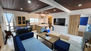 a living room with a blue couch and a kitchen at 3ベッド3バス ヴィラアパラギ宮古島 in Miyako-jima