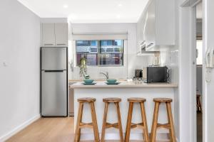 a kitchen with white cabinets and a counter with stools at Somerton Sands - Coastal Living by Glenelg South in Somerton Park +13 photos