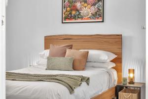 a bedroom with a bed with a wooden headboard and pillows at Somerton Sands - Coastal Living by Glenelg South in Somerton Park