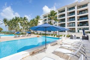 a pool with chairs and an umbrella and a building at Beachfront Luxury 2BR-Villa Acqua Rio Mar in Carmelita +55 photos