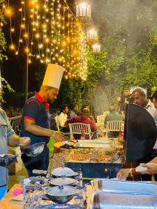 a man in a chefs hat preparing food on a grill at Avinka Grand in Talagala +111 photos