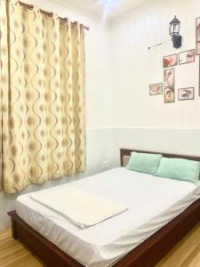 a bedroom with a bed with white sheets and a window at Khách sạn Tân Cửu Long in Bình Chánh