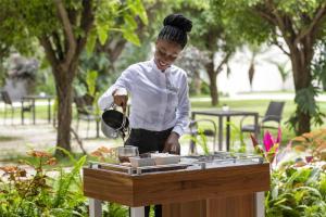 a woman is preparing food on a grill at Kempinski Hotel Gold Coast City in Accra