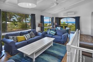 un salon avec des canapés bleus et une table dans l'établissement Baycation House Huskisson, à Huskisson