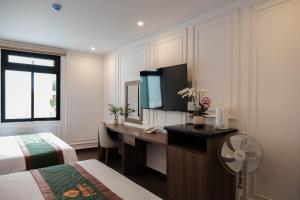 a hotel room with a desk with a television and a bed at AS Hotel Đà Lạt in Da Lat