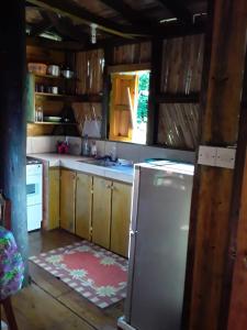 a kitchen with wooden cabinets and a stainless steel refrigerator at Tia's Bamboo Cottages Restaurant, Bar & Sulphur Spa in Roseau