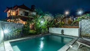a swimming pool in front of a house at night at Pondok Loris Villa in Ubud
