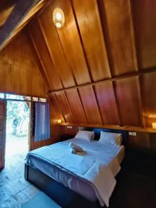 a bed in a room with a wooden ceiling at Forest Side Bungalow in Tetebatu