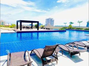 a swimming pool with chairs and a gazebo at Jojie's Crib Taft East Gate Studio in Cebu City