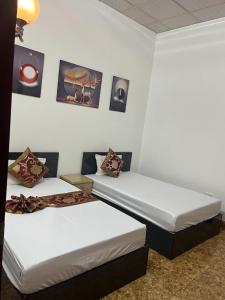 two beds in a room with pictures on the wall at Hồng Trà Hotel Quảng Ninh in Quang Ninh