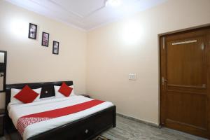 a bedroom with a bed with red pillows and a door at Hotel Krishna Resorts in Mathura