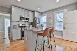 a kitchen with white cabinets and bar stools at Stylish Apartment Near Downtown, Highways, Boston in North Andover