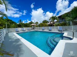 a swimming pool at a resort with blue and white chairs at Sunset Lane Apartment Hotel in Saint James